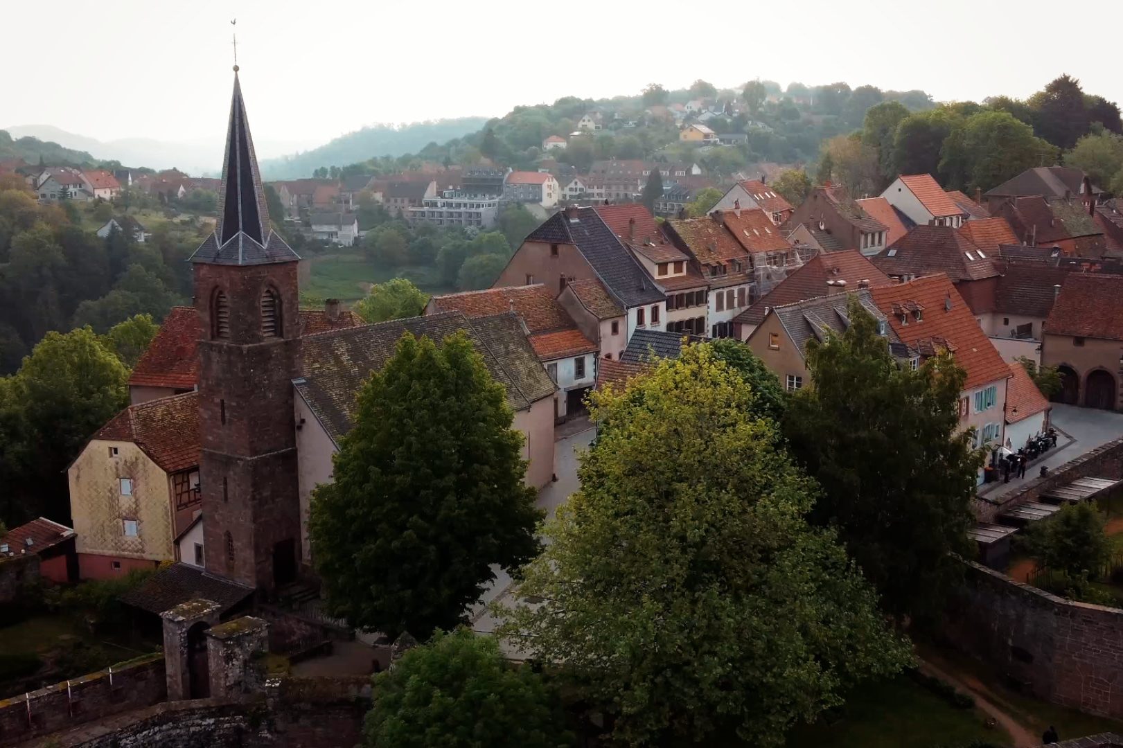 Panoramablick auf eine malerische Stadt mit Kirche und grünen Bäumen im Vordergrund.