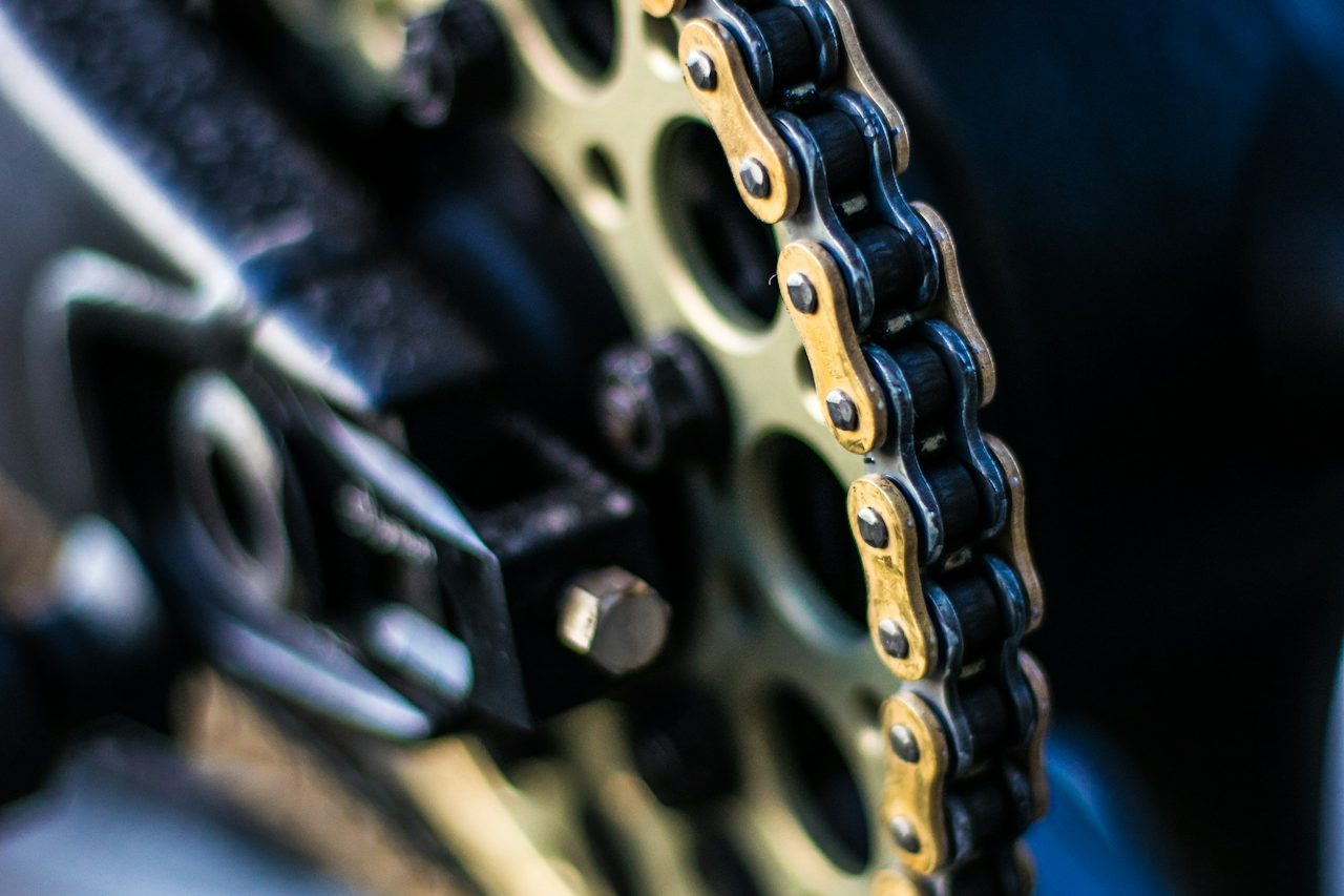 Detailaufnahme einer Motorradkette und Zahnradmechanik.